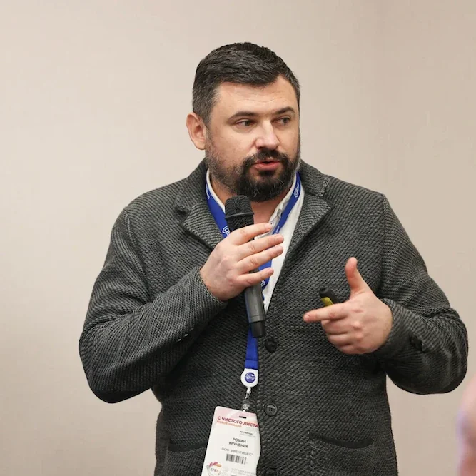 Роман Крученик говорит в микрофон, выступая на конференции